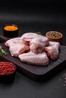 Raw chicken wings with salt, spices and herbs on a wooden cutting board photo