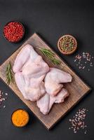 Raw chicken wings with salt, spices and herbs on a wooden cutting board photo