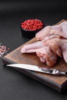 Raw chicken wings with salt, spices and herbs on a wooden cutting board photo