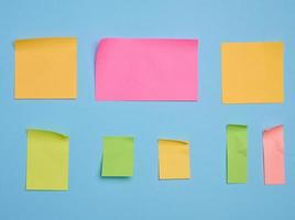 Colorful paper memo holders on blue background, space for writing data, notes photo