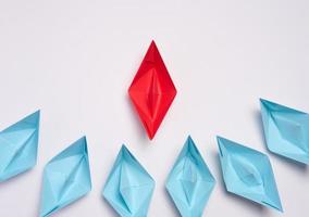 A group of blue paper boats surrounded one red boat, the concept of bullying, search for compromise. Top view photo