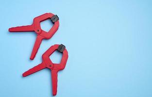 Large  red plastic clamp on a blue background, copy space photo