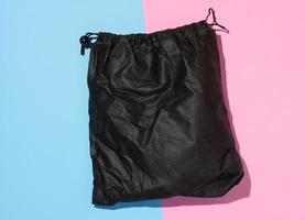 Black textile bag with a rope on a blue pink isolated background, photo