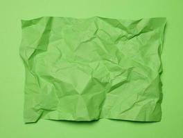 Crumpled rectangular sheet of green paper on a green background, top view. Place for inscription photo