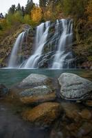 un cascada en otoño con piedras en el primer plano foto