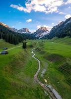 Aerial view of a valley, houses standing on a meadow hiking trails and streams leading towards mountains photo