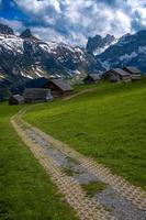 a winding road leads to the farm in the mountains, under dramatic skies photo