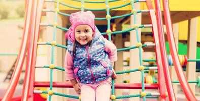 Portrait of Happy little blond girl playing on a rope web playground outdoor photo