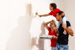 Happy family mother and child daughter making repairs, paint the wall at home photo