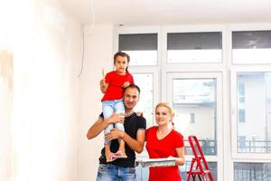 sonriente joven amoroso familia posando en su nuevo casa, reubicación y hogar mejora concepto foto