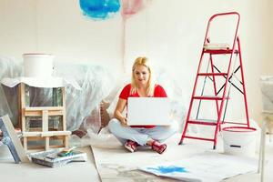 joven mujer retrato mientras pintura nuevo Departamento ,sesión con ordenador portátil. joven mujer con ordenador portátil foto