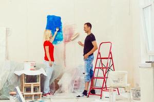 Home makeover and renovation young happy couple painting their new house interiors using paint rollers photo