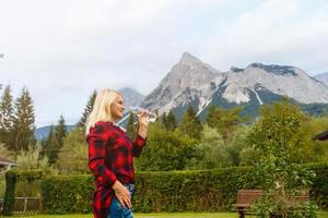 Alpes. un mujer Bebiendo agua desde un botella y admirativo el montaña escenario. foto