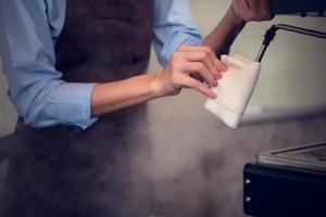 By cleaning it with a clean cloth and activating the steam to discharge the empty milk frother, the barista cleans the milk frother photo