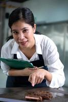 Portrait of student cooking apprentice Take notes on every step as the chef cooks in the culinary academy's kitchen. photo