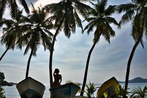 joven mujer en barco debajo el Coco arboles foto