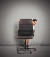 Businesswoman hiding behind a chair photo