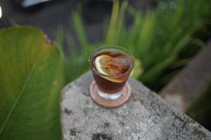 iced lemon coffee with greenery background. photo