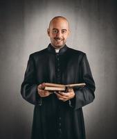sacerdote sonriente y participación un Biblia foto