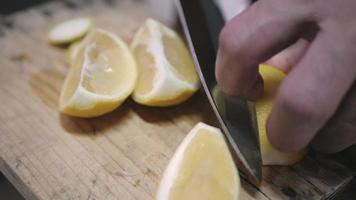 using knife to cut fresh lemon on the wooden board for making food,drink. Healthy food video