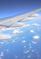 Airplane wing on blue sky with white clouds. Travel concept. photo