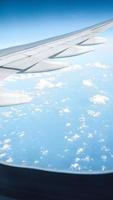 Airplane wing on blue sky with white clouds. Travel concept. photo