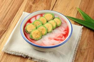 Es Pisang Ijo, Ripe Banana Rolled with Green Thin Crepes, Rice Porridge and Red Syrup. photo