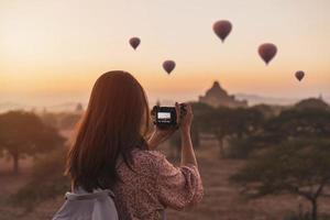 Young woman traveler enjoying with balloons over ancient pagoda at Bagan, Myanmar at sunrise photo