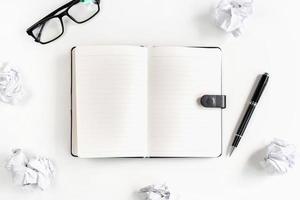 Crumpled paper balls with eye glasses and notebook on desk office, Creativity problems concept photo