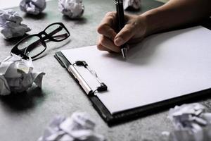 Hand writing on file folder with crumpled paper balls on desk office, Creativity problems concept photo