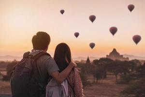 Young couple traveler enjoying with balloons over ancient pagoda at Bagan, Myanmar at sunrise