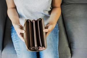 Stressed young woman open her empty wallet at home photo