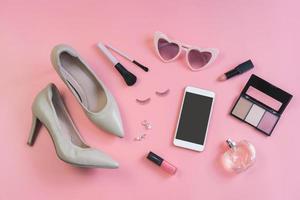 mujer productos cosméticos, accesorios y teléfono inteligente en rosado fondo, parte superior ver foto