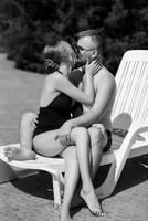 guy and a girl in bathing suits are relaxing, near the blue pool photo