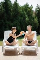 guy and a girl in bathing suits are relaxing, near the blue pool photo