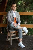 portrait of the groom in a gray suit and an orange vest photo