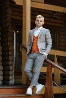 portrait of the groom in a gray suit and an orange vest photo