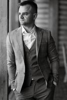 portrait of the groom in a gray suit and an orange vest photo