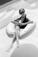 a girl in a black swimsuit floats in a blue pool photo