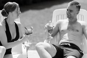 guy and a girl in bathing suits are relaxing, near the blue pool photo