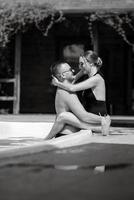 chico y un niña en baños trajes son relajante, cerca el azul piscina foto