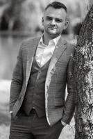 portrait of the groom in a gray suit and an orange vest photo