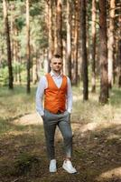 portrait of the groom in a gray suit and an orange vest photo