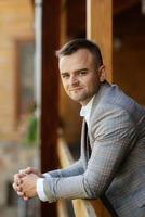 portrait of the groom in a gray suit and an orange vest photo