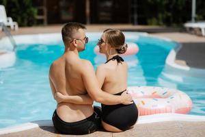 chico y un niña en baños trajes son relajante, cerca el azul piscina foto