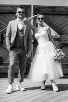 young couple bride in a white short dress and groom in a gray suit near the wooden gate photo