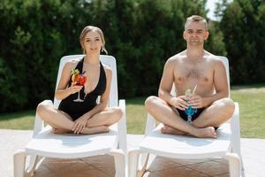 guy and a girl in bathing suits are relaxing, near the blue pool photo