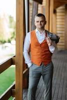 portrait of the groom in a gray suit and an orange vest photo