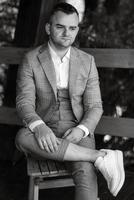 portrait of the groom in a gray suit and an orange vest photo