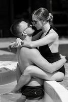 guy and a girl in bathing suits are relaxing, near the blue pool photo